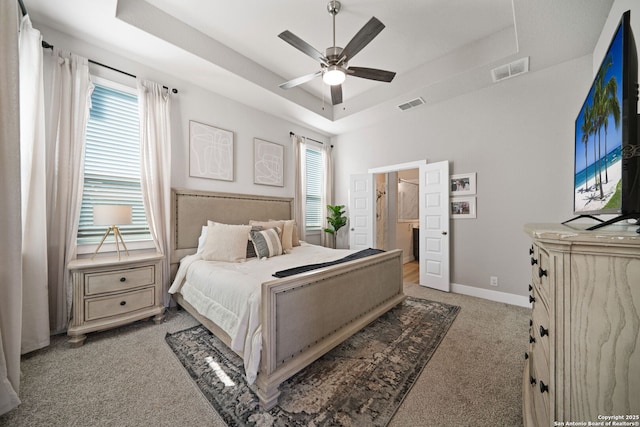 bedroom featuring a tray ceiling, baseboards, multiple windows, and visible vents