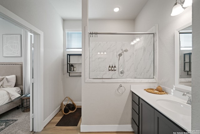 full bathroom with ensuite bathroom, wood finished floors, tiled shower, baseboards, and vanity