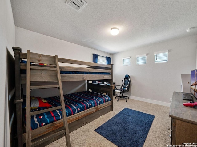 bedroom featuring visible vents, a textured ceiling, baseboards, and carpet