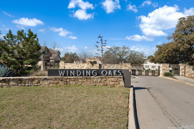 community / neighborhood sign with fence, a yard, and a gate