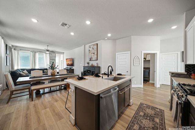 kitchen featuring visible vents, a sink, stainless steel dishwasher, gas range, and open floor plan