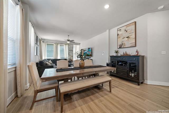 dining room featuring baseboards, a ceiling fan, and light wood finished floors