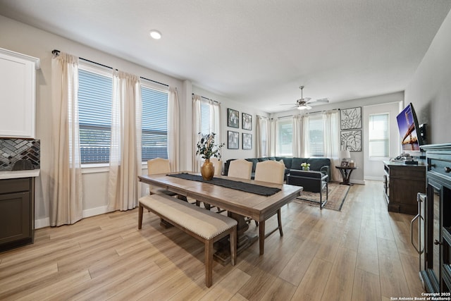 dining area with a ceiling fan, light wood-type flooring, and baseboards