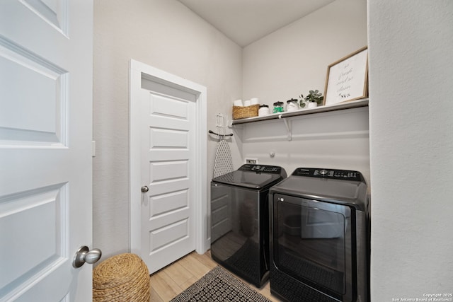 laundry area with laundry area, washing machine and dryer, and light wood finished floors