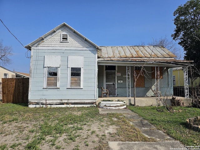 view of front facade featuring metal roof, fence, a porch, and a standing seam roof