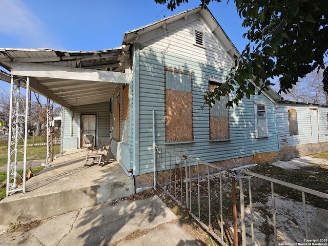 view of side of home featuring a carport and fence