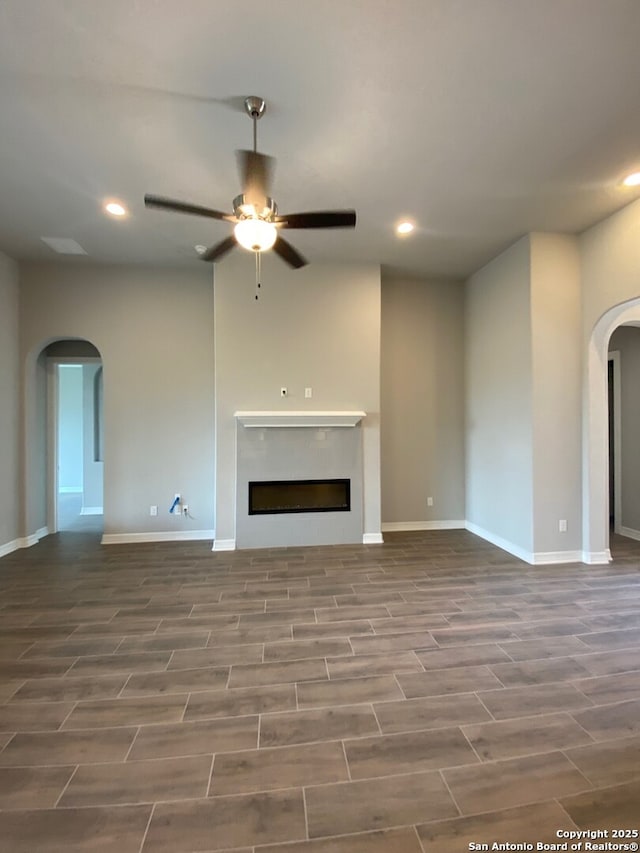 unfurnished living room with recessed lighting, arched walkways, a ceiling fan, and a fireplace