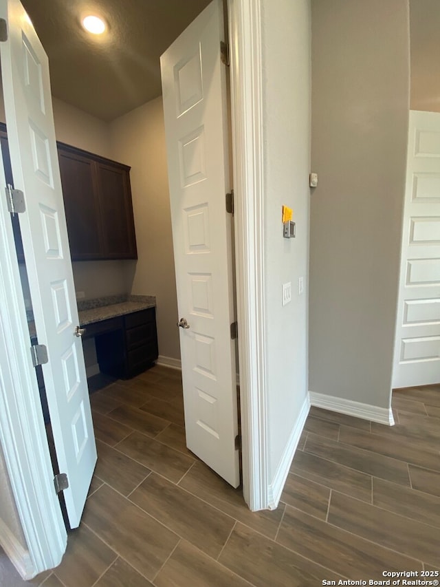 corridor with baseboards and wood finish floors