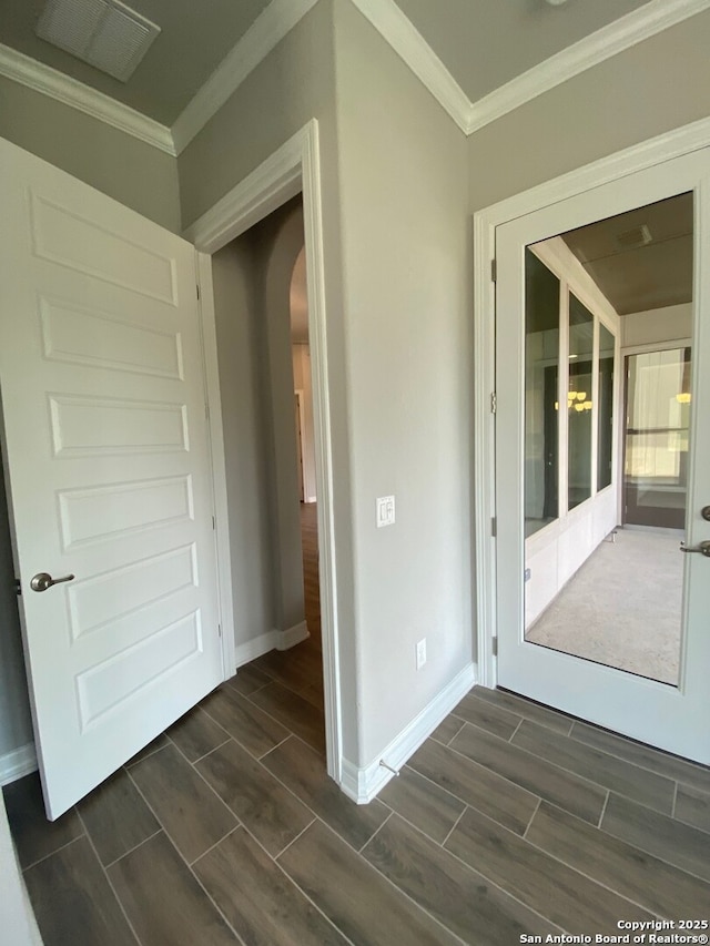 corridor with crown molding, baseboards, arched walkways, and wood tiled floor