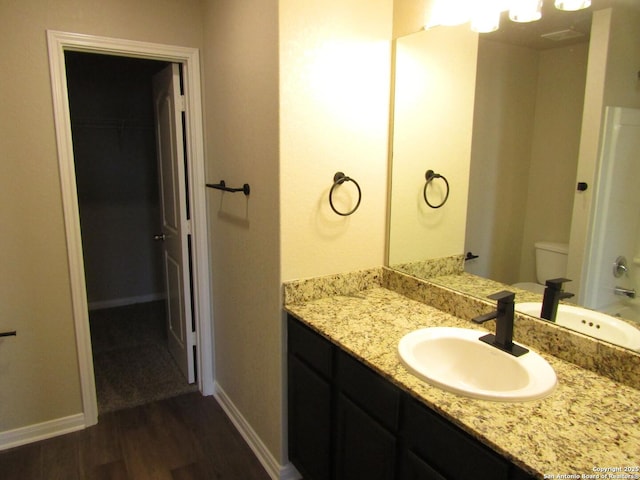 bathroom with vanity, toilet, wood finished floors, and baseboards