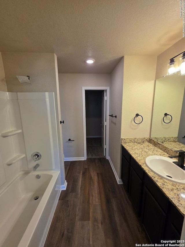 bathroom with a textured ceiling, vanity, baseboards, and wood finished floors