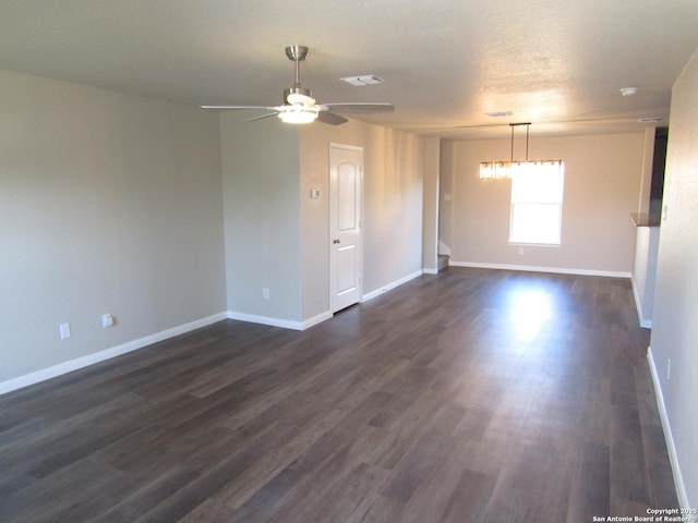 spare room with dark wood finished floors, visible vents, and baseboards