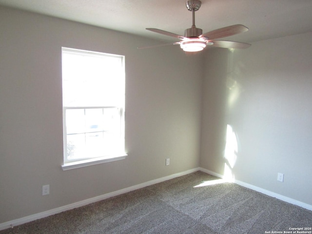 carpeted spare room with a ceiling fan and baseboards