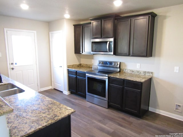 kitchen featuring baseboards, dark wood finished floors, dark brown cabinetry, recessed lighting, and stainless steel appliances