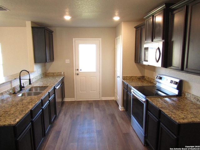 kitchen featuring a sink, dark wood-style floors, appliances with stainless steel finishes, stone counters, and baseboards