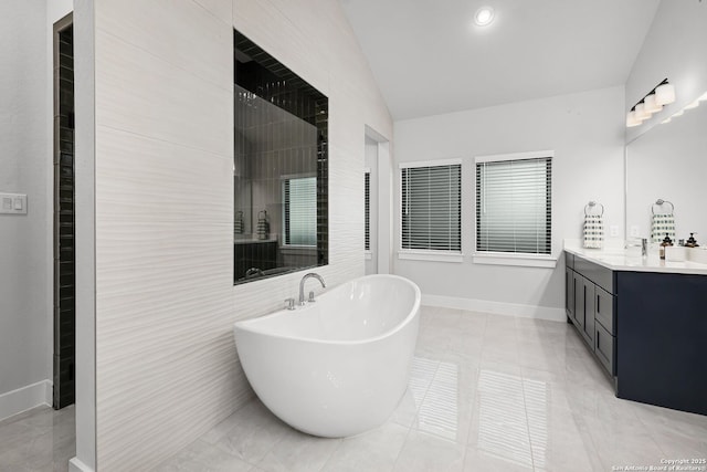 bathroom with recessed lighting, baseboards, a freestanding bath, vanity, and vaulted ceiling