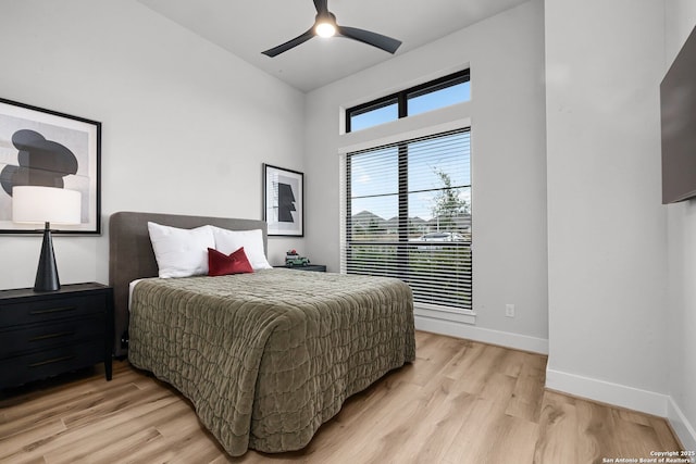 bedroom with vaulted ceiling, light wood-style flooring, and baseboards