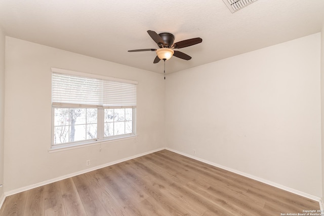 spare room featuring light wood-type flooring, visible vents, and baseboards