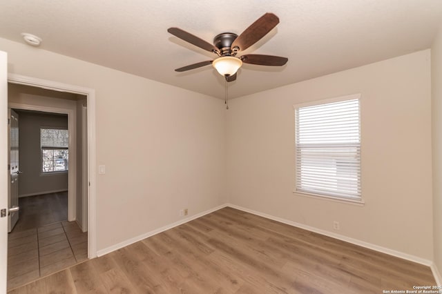 unfurnished room featuring baseboards, light wood-style floors, and a ceiling fan