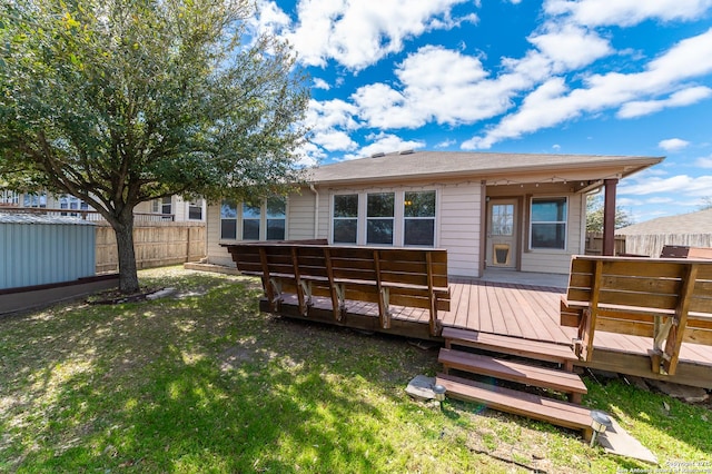 back of property featuring a yard, a deck, and fence