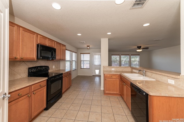 kitchen with visible vents, a sink, black appliances, light countertops, and backsplash