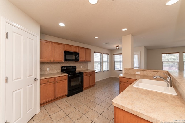 kitchen with backsplash, black appliances, light countertops, and a sink