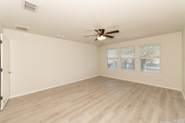 unfurnished room with visible vents, light wood-style flooring, a ceiling fan, and baseboards