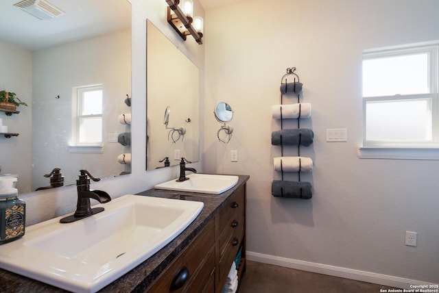 bathroom with double vanity, visible vents, baseboards, and a sink