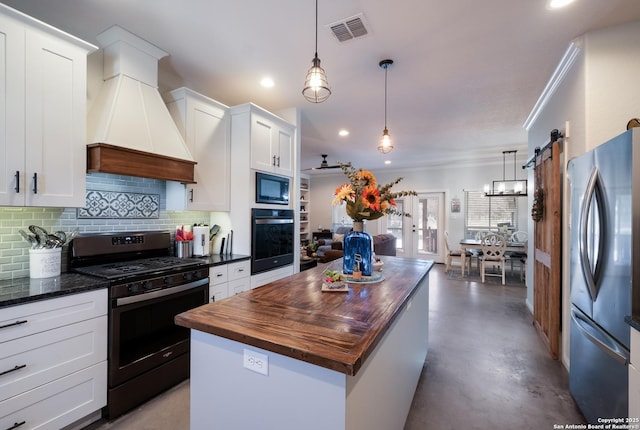 kitchen with visible vents, premium range hood, a kitchen island, stainless steel appliances, and butcher block counters