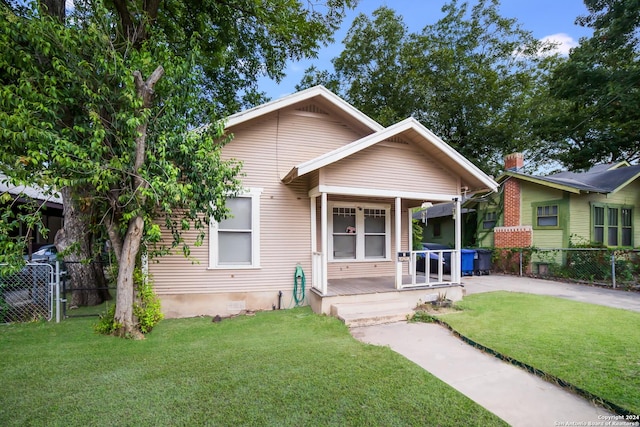 bungalow-style home featuring driveway, a front lawn, and fence