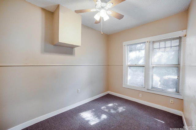 unfurnished room featuring dark carpet, a ceiling fan, and baseboards