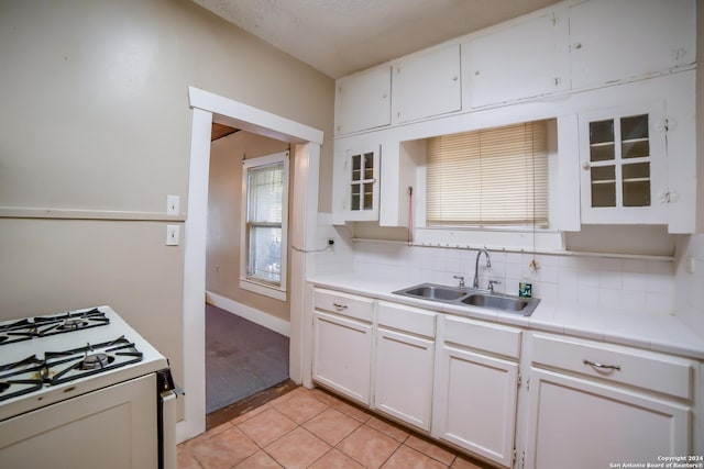 kitchen featuring decorative backsplash, white cabinetry, gas range gas stove, and a sink