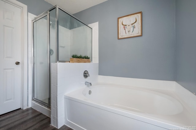 full bath with a shower stall, a garden tub, and wood finished floors