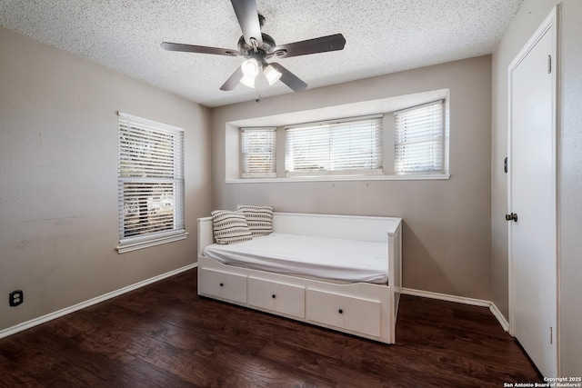 bedroom with ceiling fan, baseboards, a textured ceiling, and wood finished floors