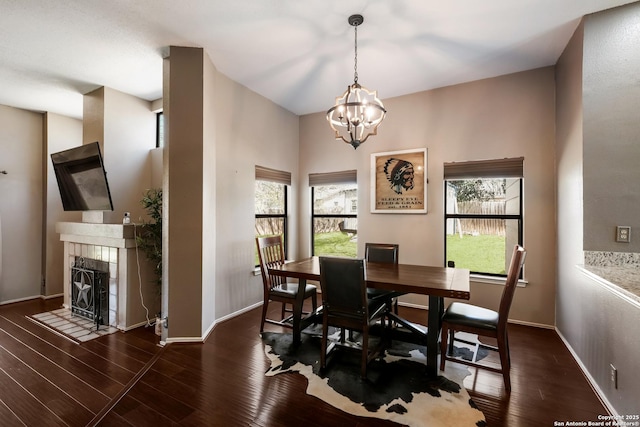 dining room with a tiled fireplace, a wealth of natural light, and wood finished floors