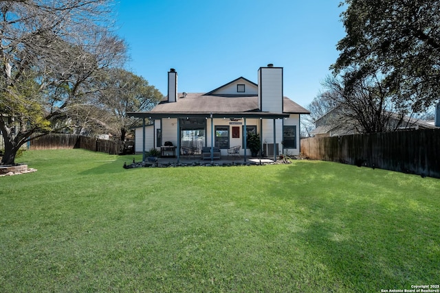 rear view of property with a patio, a yard, a fenced backyard, and a chimney