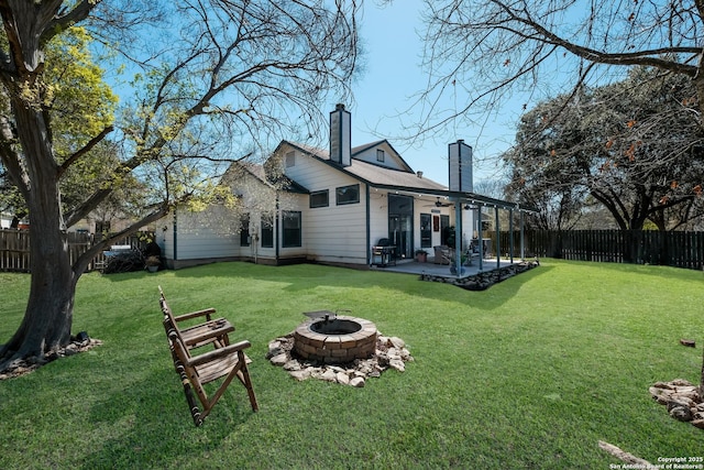 back of property featuring a ceiling fan, a fenced backyard, a yard, a fire pit, and a chimney