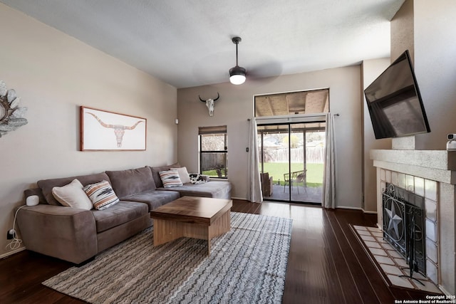 living room featuring baseboards, dark wood finished floors, and a tile fireplace