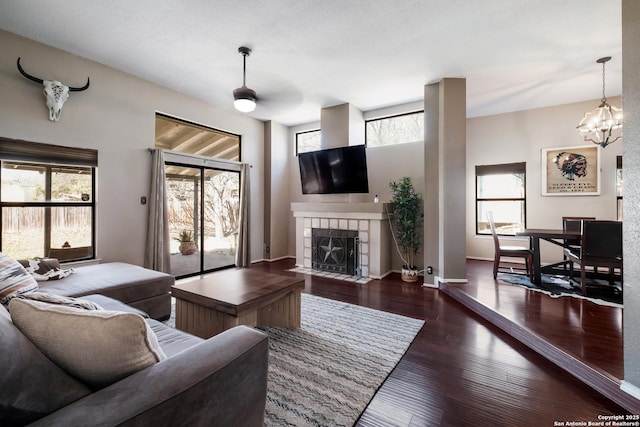 living room with wood finished floors, a notable chandelier, a fireplace, and baseboards