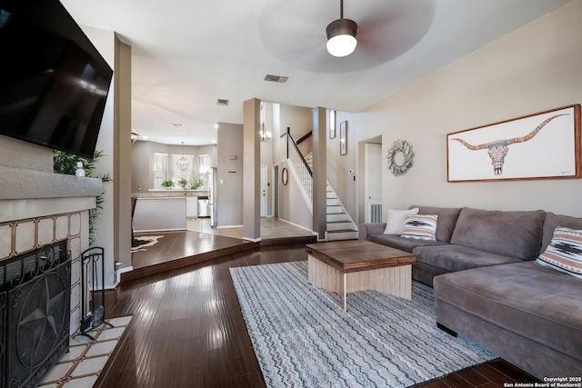 living room featuring a tiled fireplace, hardwood / wood-style flooring, stairway, and visible vents