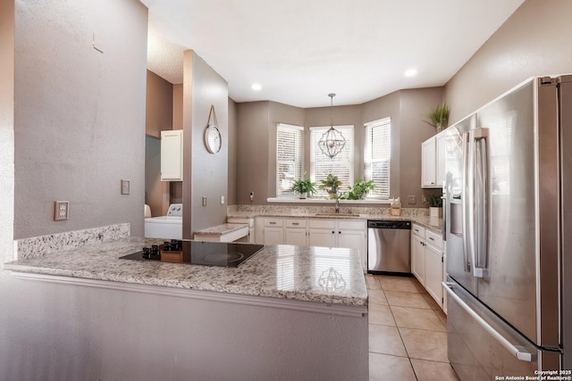 kitchen with a sink, washer / clothes dryer, a peninsula, appliances with stainless steel finishes, and white cabinets