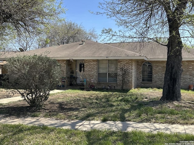 view of front facade featuring brick siding and roof with shingles