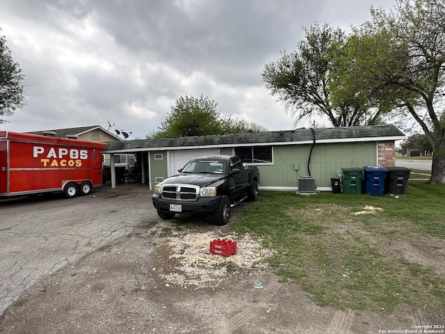 exterior space featuring an attached carport, central AC unit, and driveway