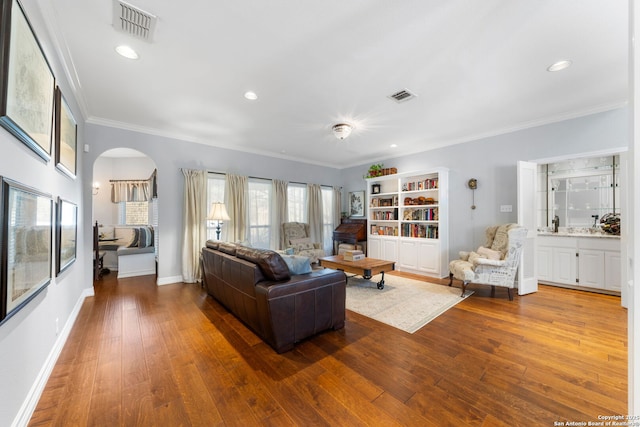 living area featuring visible vents, hardwood / wood-style floors, and ornamental molding