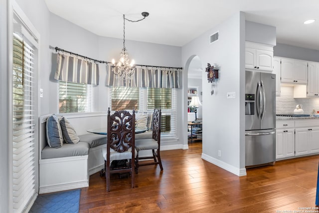 dining space with a notable chandelier, visible vents, arched walkways, and hardwood / wood-style flooring