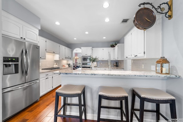 kitchen with a peninsula, white cabinets, and stainless steel appliances