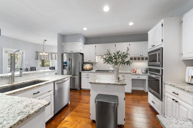 kitchen with dark wood finished floors, decorative backsplash, light stone countertops, and appliances with stainless steel finishes