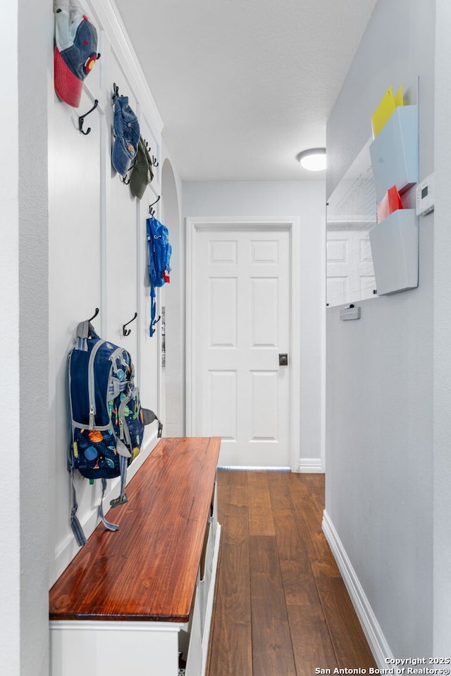 interior space with dark wood finished floors, arched walkways, and baseboards