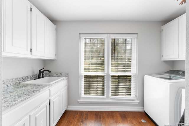 washroom with baseboards, dark wood finished floors, washer / clothes dryer, cabinet space, and a sink