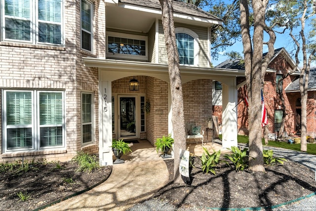 doorway to property with covered porch and brick siding